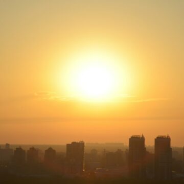 Liana S / Unsplash Blazing sun rising over a silhouetted city skyline